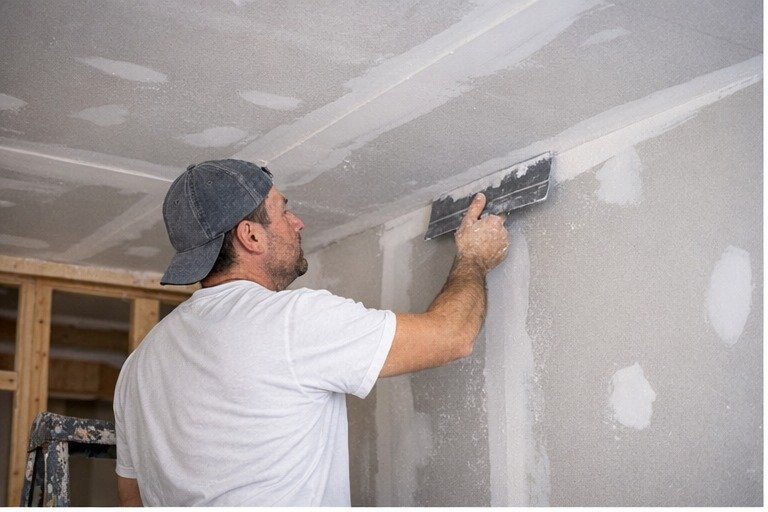 Worker smoothing drywall seams